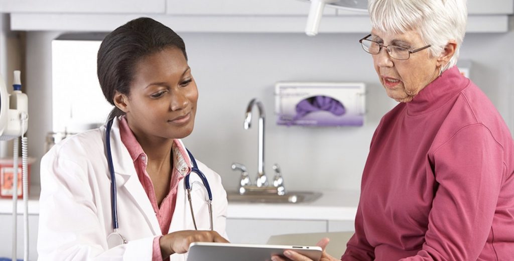 Woman doctor showing older patient clipboard
